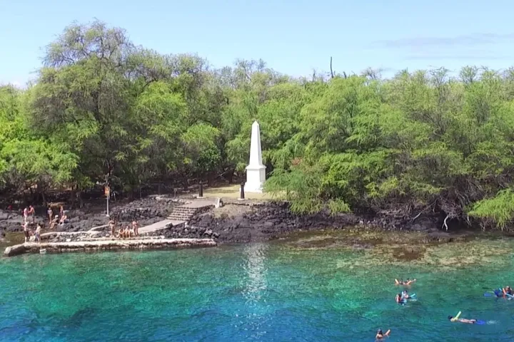 captain cook monument with swimmers on a sunny day