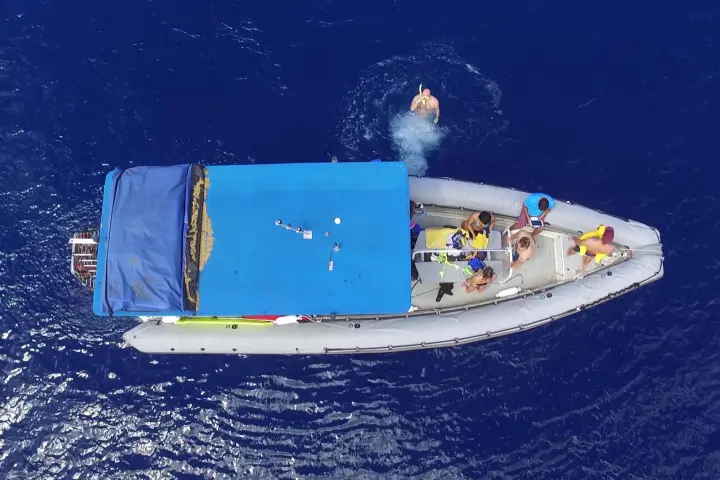 overhead shot of boat with people jumping off