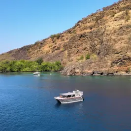 a small boat in a body of water with a mountain in the background