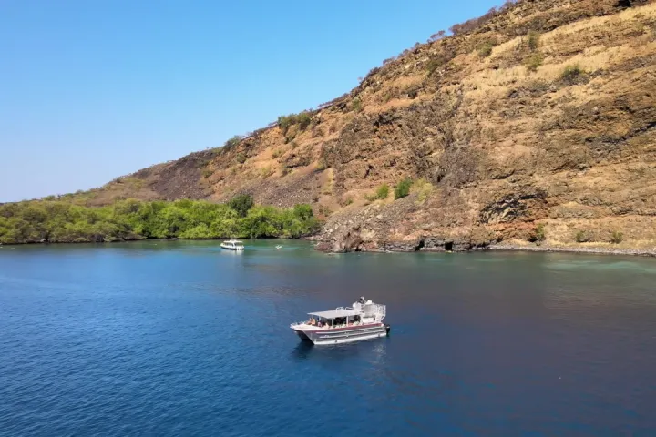 a small boat in a body of water with a mountain in the background